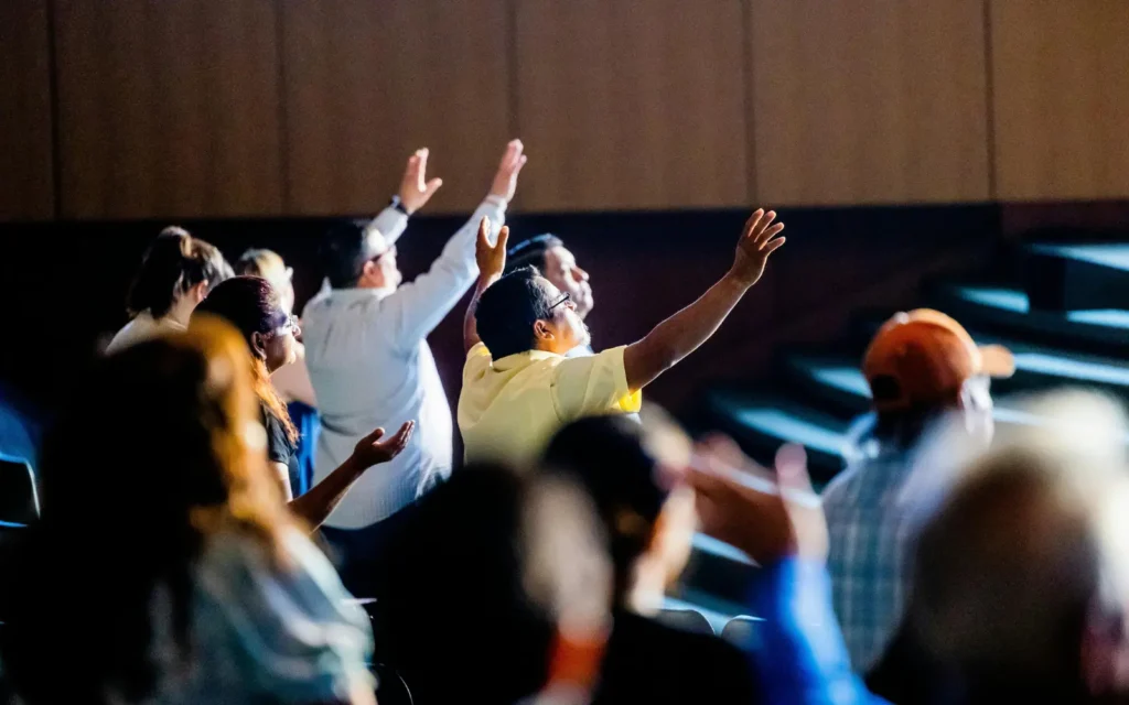 People with arms raised worshipping in church, representing church growth through Digital Evangelist